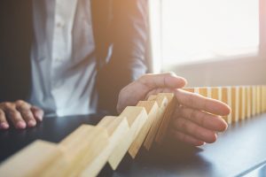 Close up view on hand of business woman stopping falling blocks on table