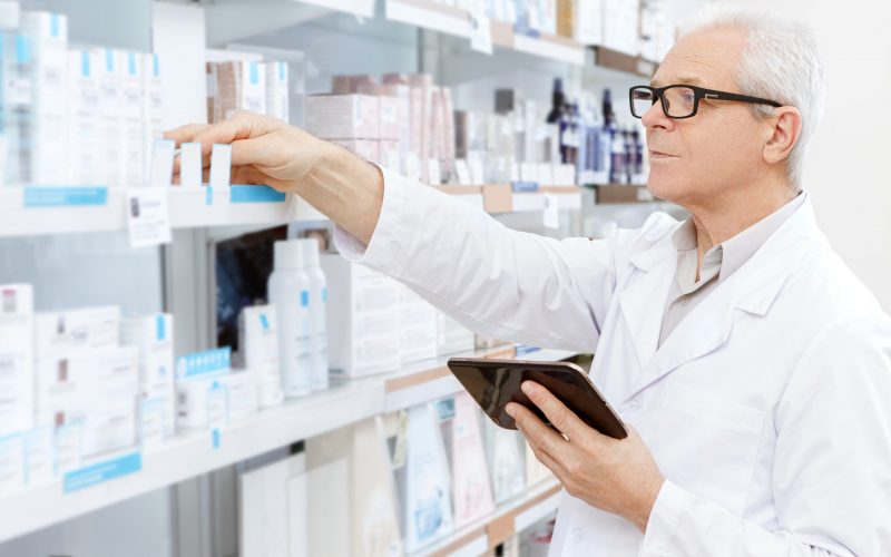 Running his business online. Elderly pharmacist checking stock in an aisle at his pharmacy ordering medications online using digital tablet running his small business pharmacy online shopping concept