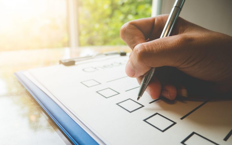 Close- up hand holding pen on check list paper and the format for filling in information in business concept,vintage style and softtone