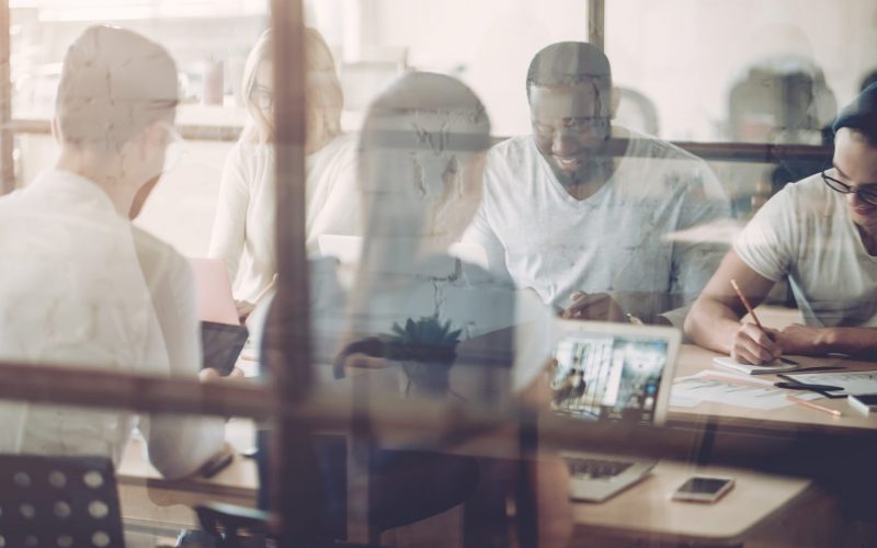 Multiracial young creative people in modern office. Group of young business people are working together with laptop, tablet, smart phone, notebook. Successful hipster team in coworking. Freelancers.