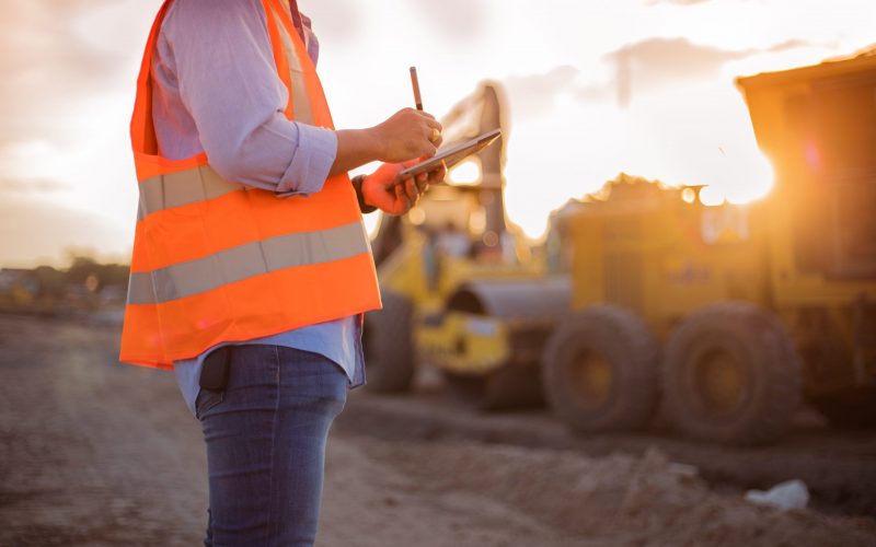Asian engineer with hardhat using  tablet pc computer inspecting and working at construction site