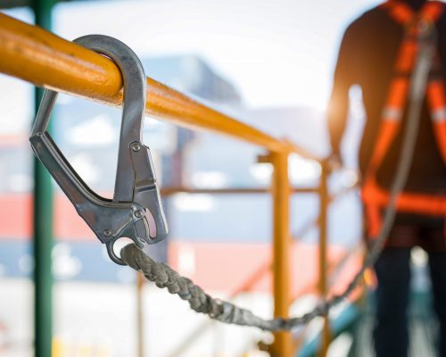 Construction worker wearing safety harness and safety line working at high place