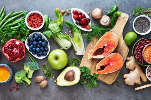 Healthy food selection: food sources of omega 3 and unsaturated fats, fruits, vegetables, seeds, superfoods with high vitamin e and dietary fiber, cereals on gray background