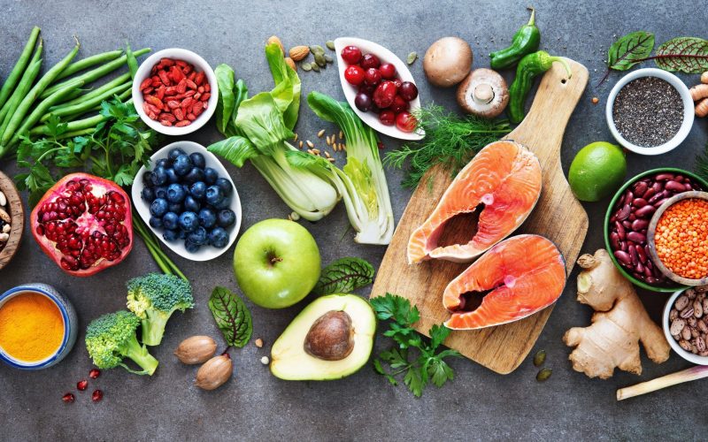 Healthy food selection: food sources of omega 3 and unsaturated fats, fruits, vegetables, seeds, superfoods with high vitamin e and dietary fiber, cereals on gray background