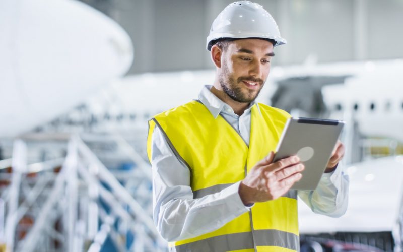 Portrait of Aircraft Maintenance Mechanic in Safety Vest using Tablet Computer