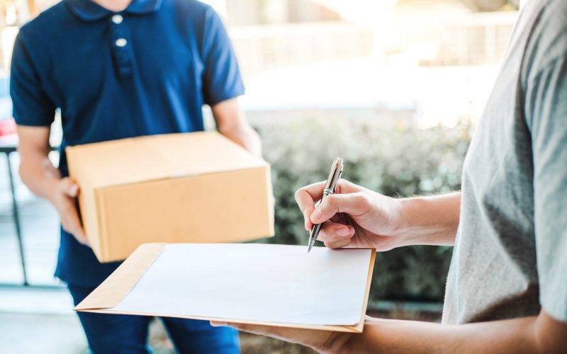 Customer Man signature in clipboard to receive package from professional delivery man at home